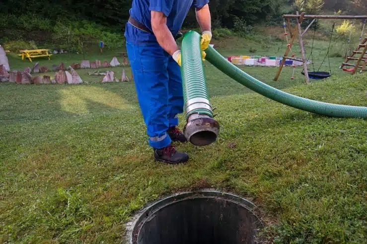Technicien effectuant la vidange d'une fosse septique avec tuyau